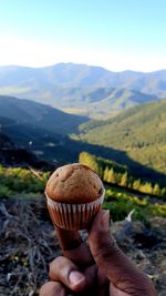 Midsection of person holding ice cream on mountain