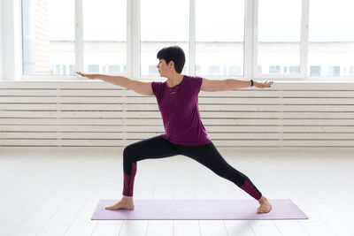 Full length of woman with arms raised on floor