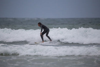 Full length of man surfing in sea against sky