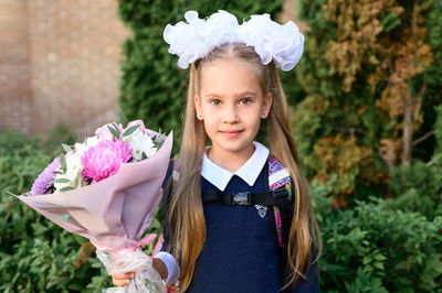 Portrait of cute girl standing by flowering plants