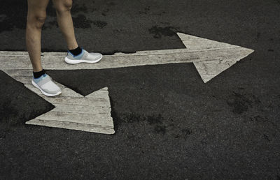 Low section of person standing on road sign