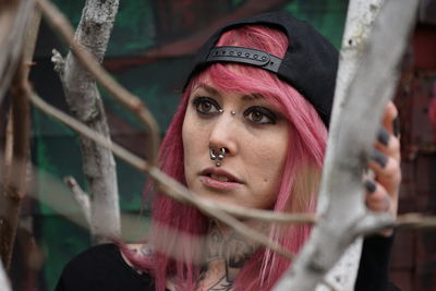 Close-up of woman with pink hair by plant