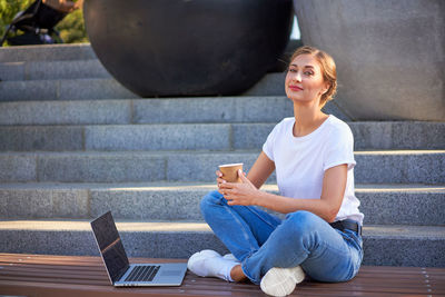 Smiling young woman sitting on staircase