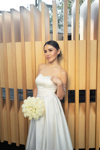 Portrait of young woman standing against wall