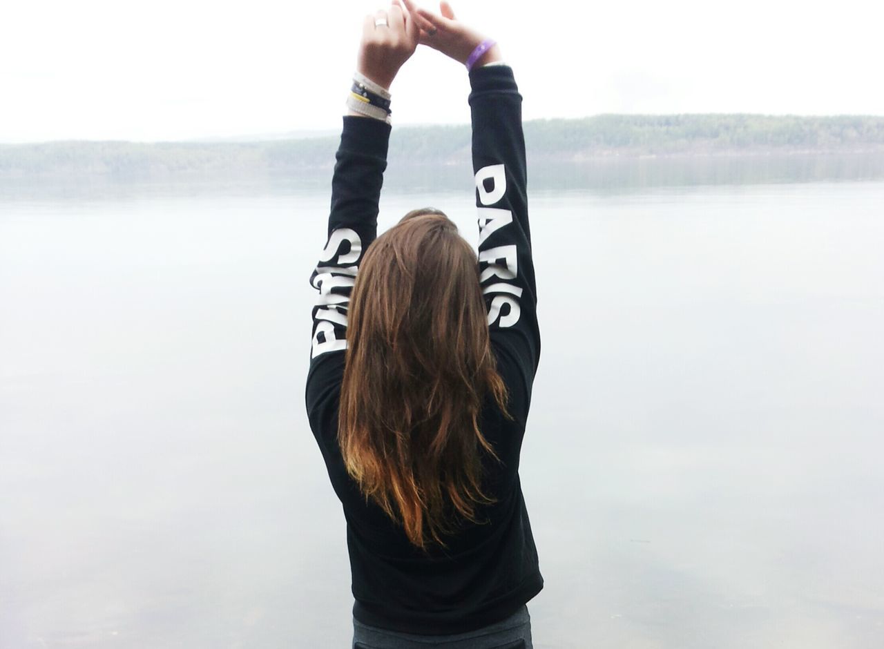 lifestyles, standing, leisure activity, rear view, waist up, casual clothing, three quarter length, young adult, focus on foreground, communication, water, long hair, person, clear sky, sea, holding, side view, tranquility