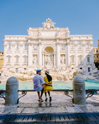 Rear view of man and woman standing against building