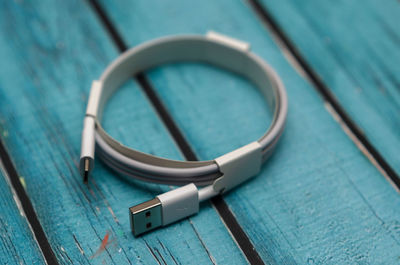 Usb type cable with white color on a blue wooden background in blur.