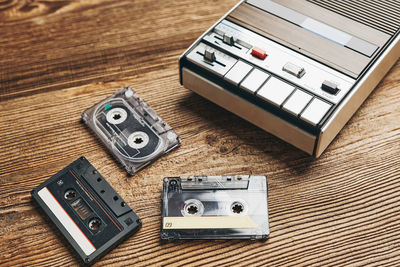 Compact cassette tapes and cassette recorder on wooden table. retro music style. 80s music party