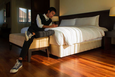 Young woman using laptop while sitting on bed at home