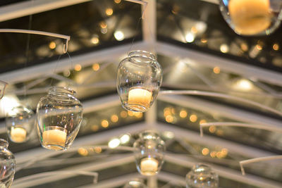 Low angle view of lit tea light candles hanging indoors