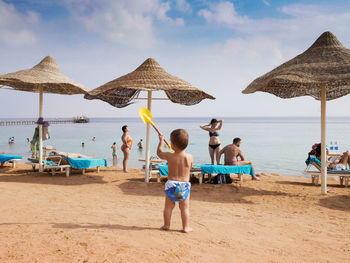 Rear view of people on beach against sky