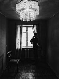 Side view of man standing by window at home