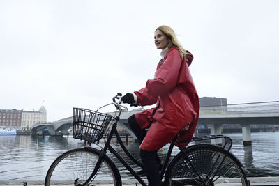 Denmark, copenhagen, woman riding bicycle at the waterfront in rainy weather