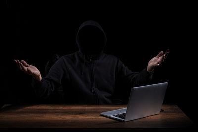 Midsection of person using laptop on table against black background