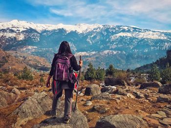 Rear view of woman standing on rock against sky