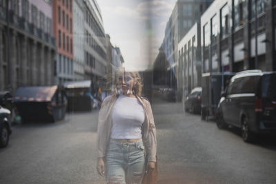 Double exposure of beautiful young woman walking in front of buildings on 