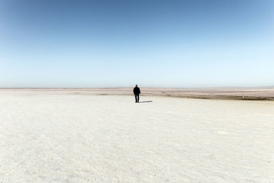 Full length of woman walking on beach against clear sky