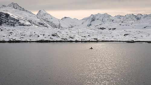 Scenic view of lake by snowcapped mountains against sky