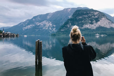 Rear view of woman looking at lake against mountains