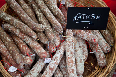 High angle view of dry sausages in wicker basket for sale at market stall