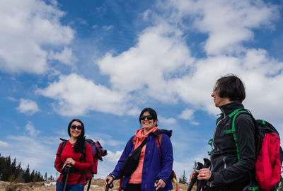 Low angle view of friends standing against sky