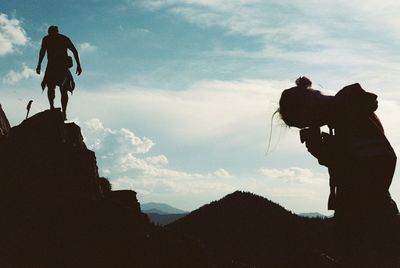 Silhouette people standing on mountain against sky