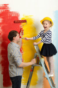 Cheerful of father and daughter painting wall