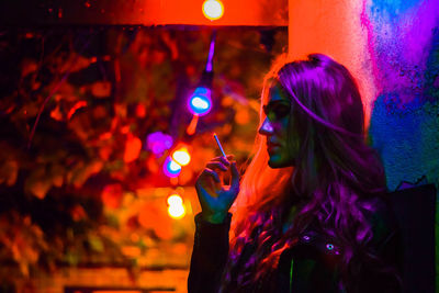 Close-up of woman holding colorful light painting at night
