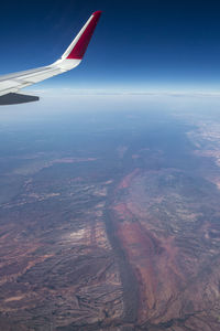 Aerial view of airplane wing over landscape against sky