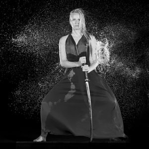 Portrait of a young woman with umbrella standing against black background