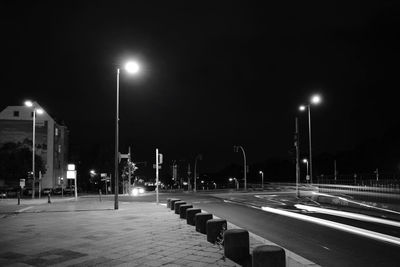 Empty road against illuminated street lights in city at night