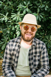 Portrait of young man wearing sunglasses while standing against plants