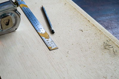 Metal ruler, carpenter's pencil and measuring tape on the wooden plank. view in the workshop