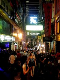 People on illuminated street in city at night