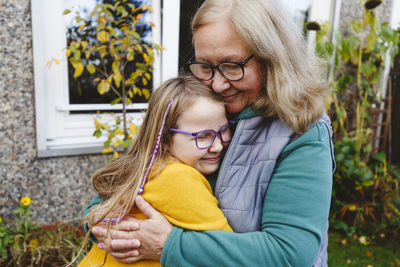 Smiling senior woman embracing granddaughter