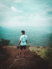 Rear view of man standing on land against sky