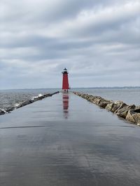 Lighthouse by sea against sky