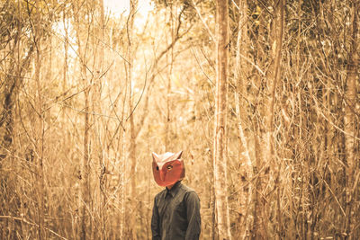 Portrait of person standing alone in the forest with mask