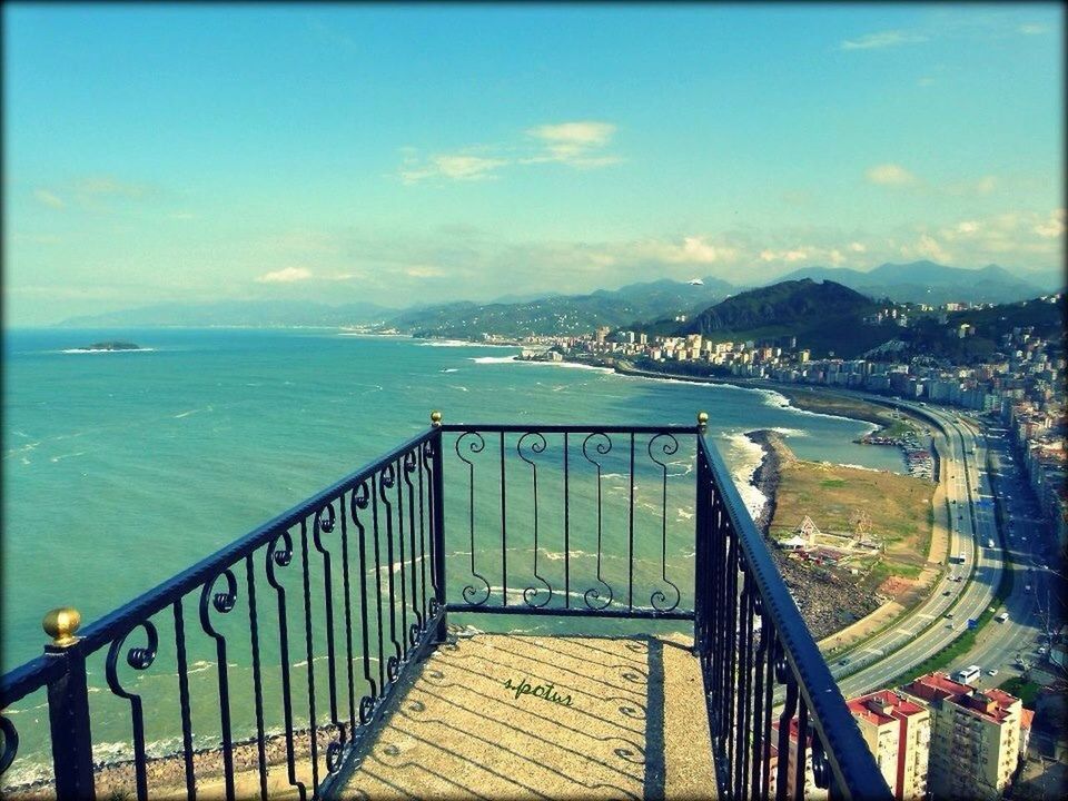 sea, railing, sky, water, built structure, horizon over water, architecture, tranquility, tranquil scene, scenics, blue, nature, cloud - sky, beach, beauty in nature, mountain, cloud, transfer print, outdoors, day