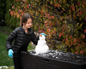 Smiling girl making snowman outdoors