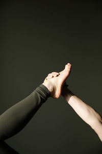 Midsection of woman exercising against black wall