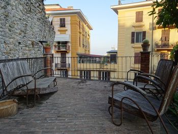 Empty chairs and tables on street amidst buildings in city