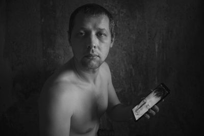 Portrait of shirtless man standing against wall