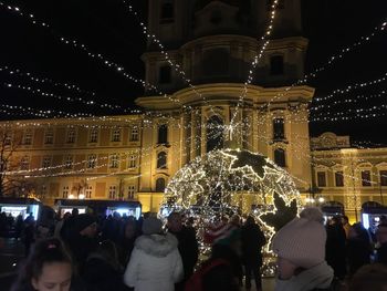 Group of people in front of illuminated christmas lights at night