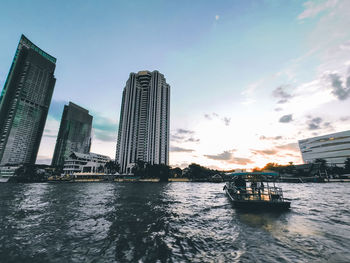 Scenic view of river by city buildings against sky