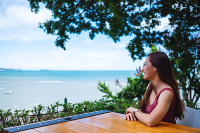 Side view of woman looking at sea against sky