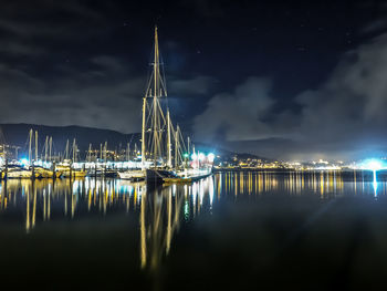 Illuminated ship moored at harbor against sky at night