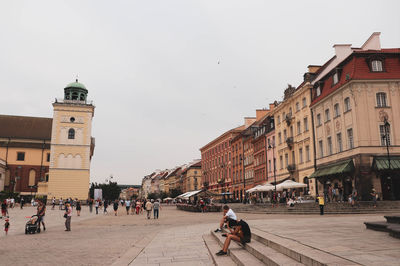 People walking on street against buildings in city