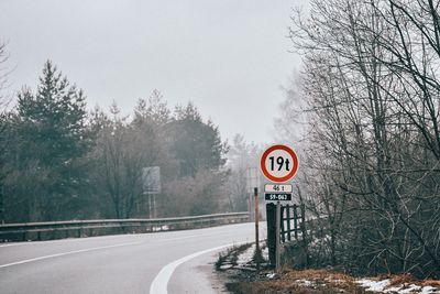 Road sign by trees during winter