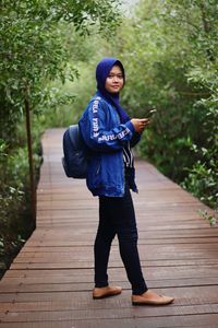 Full length portrait of woman standing on footpath